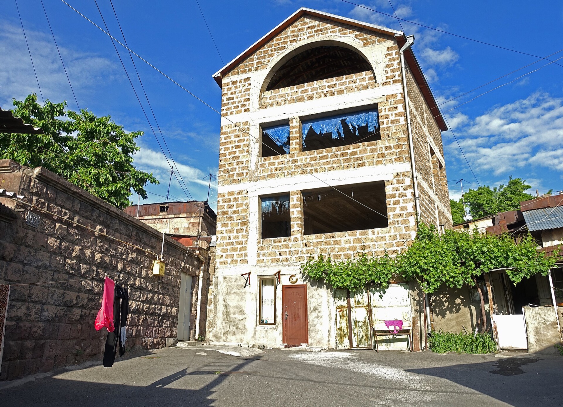 Stone house, courtyard walls, vines, and overhead wires in Kond, Yerevan