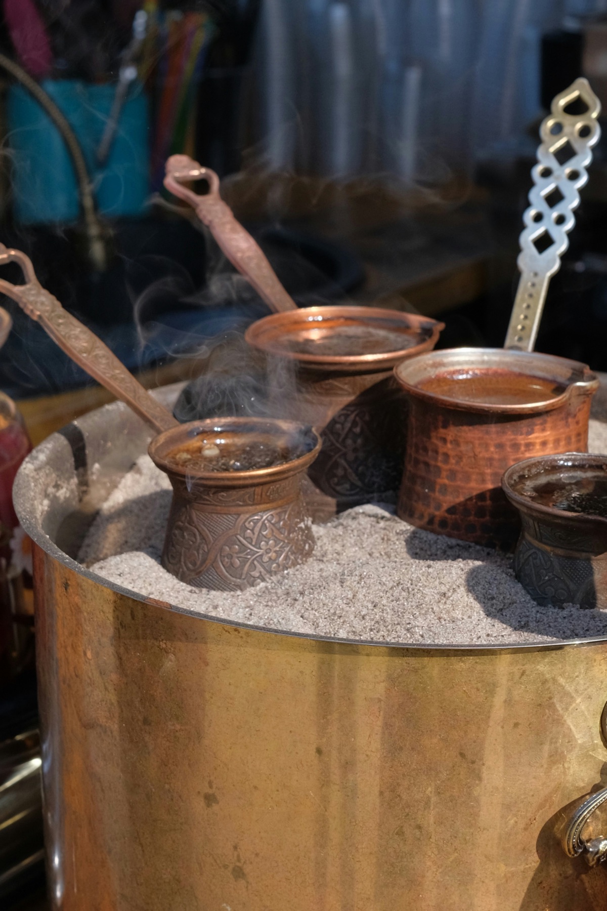 Traditional Armenian coffee brewing in copper pots over hot sand in Yerevan